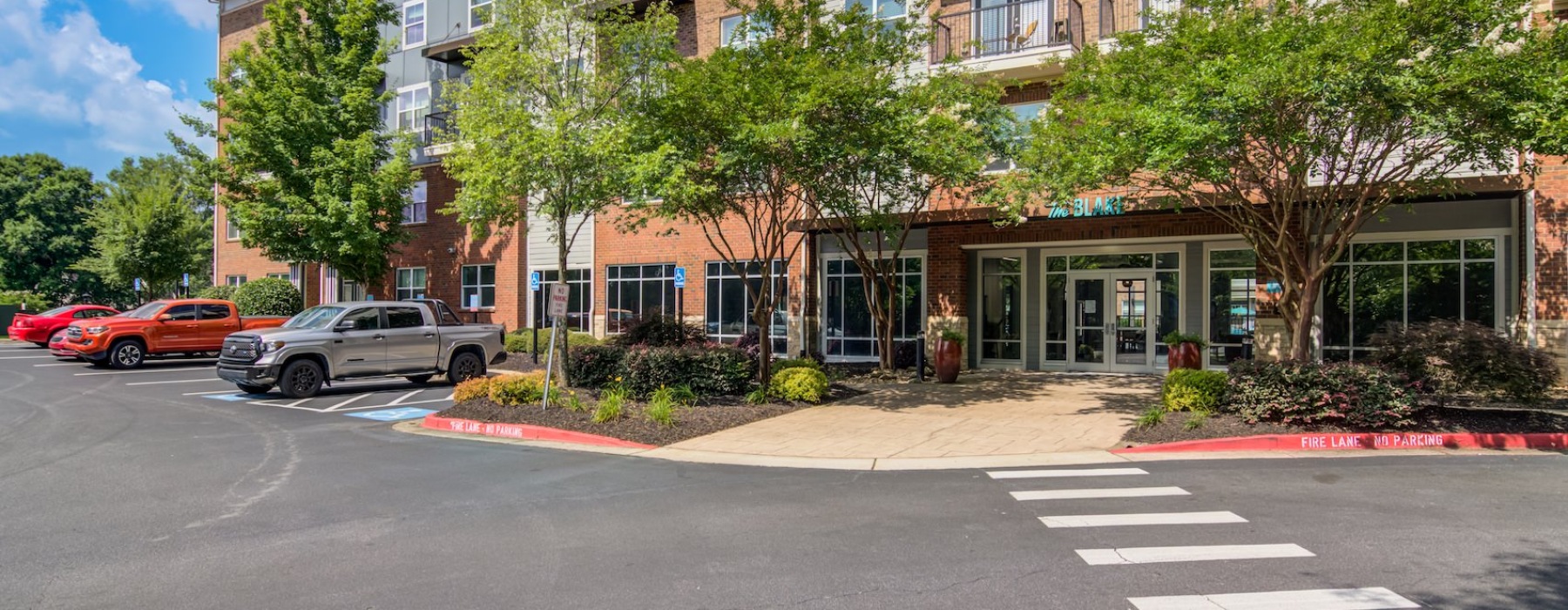 the exterior of a brick building near trees and a parking lot
